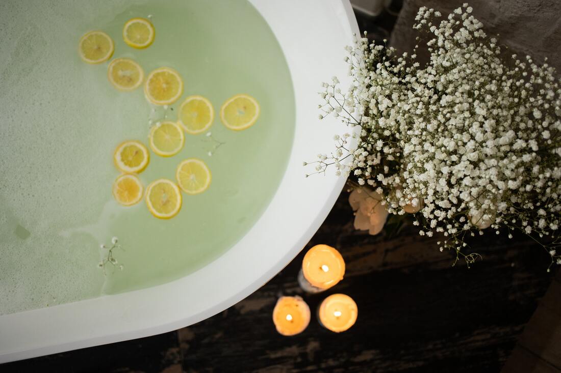 A filled bathtub with lemons floating in the water.
