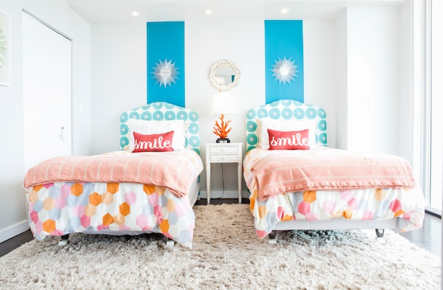 Two beds next to each other in a children's room with white and blue walls