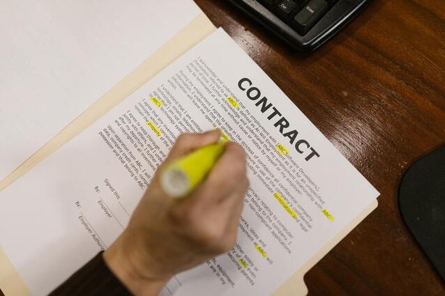  A hand with a yellow marker over a rental contract.