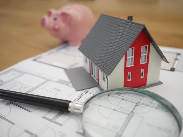 A magnifying glass, a house model, and a piggy bank
