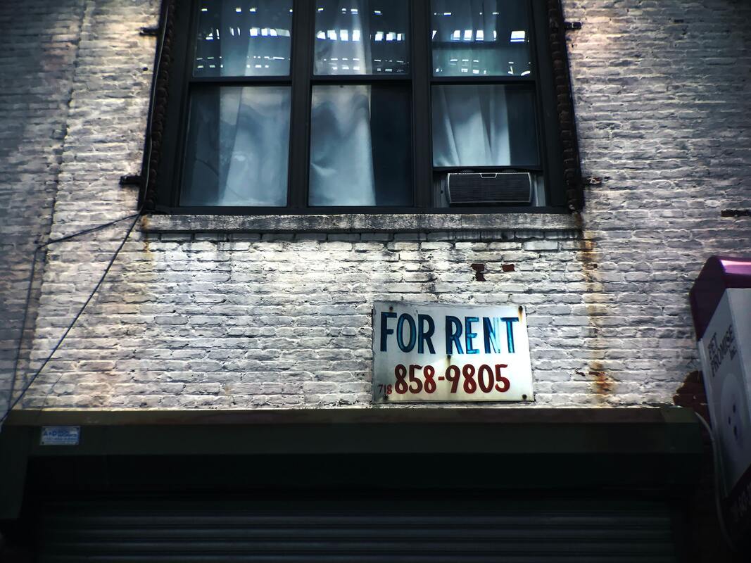 A building wall with a “for rent” sign